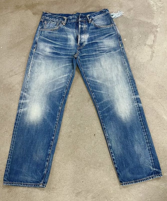 Finition denim lavage léger avec un décoloration subtil et une moustache pour un look classique